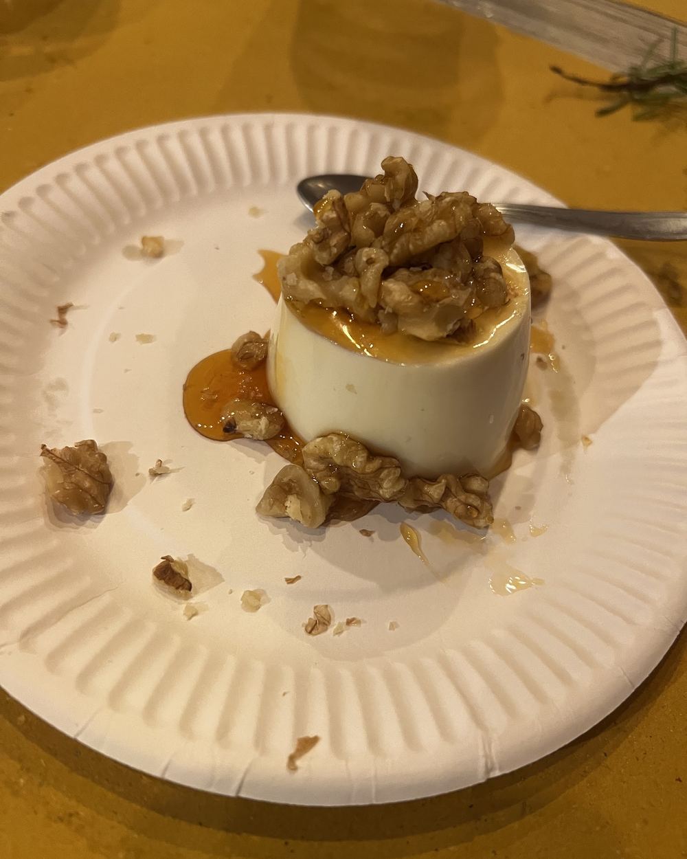 Un dolce al cucchiaio servito in una cocotte bianca, con granella e salsa al caramello sul piatto.