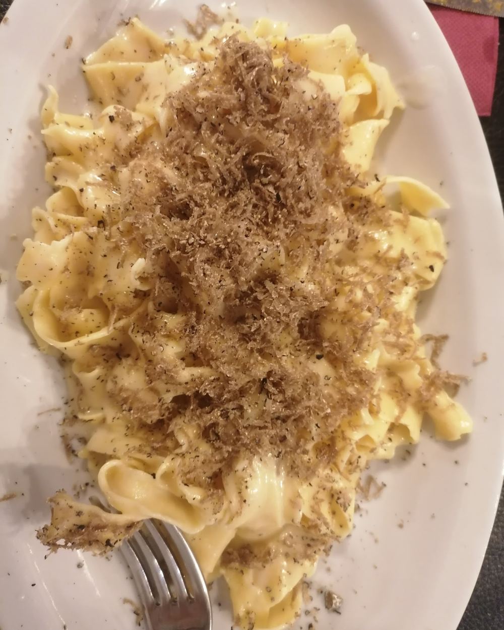 Un piatto di tagliatelle fatte a mano coperte da una grattugiata abbondante di tartufo nero fresco.